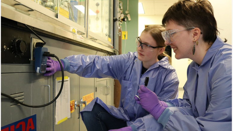 Two students in lab coats and goggles